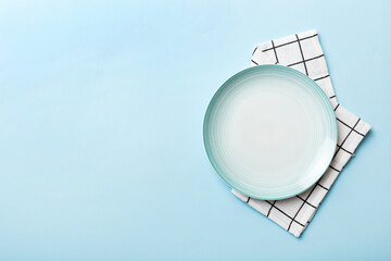 Top view on colored background empty round blue plate on tablecloth for food. Empty dish on napkin...