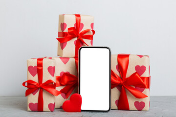 mobile phone with blank screen on colored background with hearts, calendar and gift box, valentine day concept perspertive view flat lay