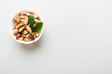 Fresh healthy Brazil nuts in bowl on colored table background. Top view Healthy eating bertholletia concept. Super foods