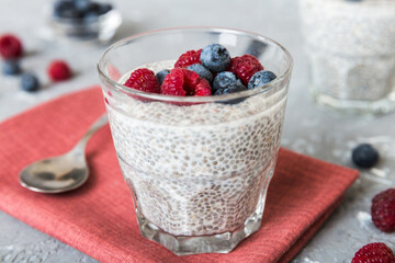 Healthy breakfast or morning with chia seeds vanilla pudding raspberry and blueberry berries on table background, vegetarian food, diet and health concept. Chia pudding with raspberry and blueberry