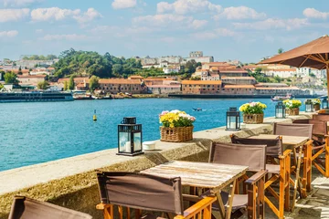 Fotobehang View of open-air street cafe on the banks of the River Douro in Porto, Portugal © Picturellarious