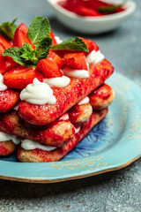 Tiramisu. Homemade tiramisu cake with fresh strawberry, mascarpone and mint. Tiramisu portion on plate on dark background. Delicious no bake tiramisu