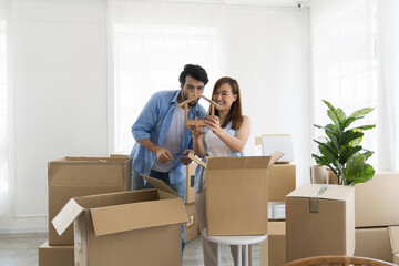 Moving house, mortgage, family and real estate concept. Happy couple inspecting quality stuff in cardboard boxes while moving into new house. Man, woman checking stuff in boxes during moving new home