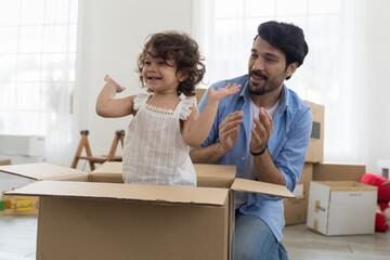 Moving house, mortgage, family and real estate concept. Happy father and cute little daughter baby toddler girl playing inside of cardboard box family moving into new house