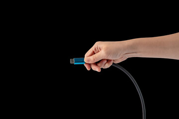 Hand and HDMI cable connector isolated on black background.