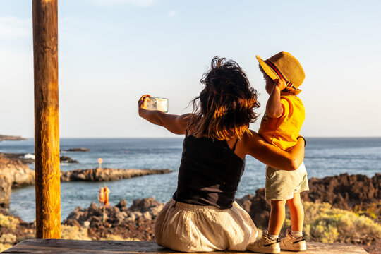 Mother and son on vacation taking a photo on Tacoron beach in El Hierro, Canary Islands. Having fun, boy in a hat