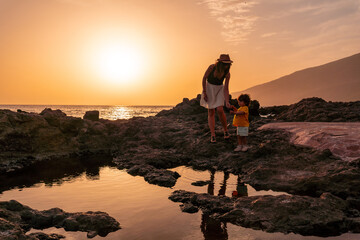 Mother and son at sunset on the beach of Tacoron on El Hierro, Canary Islands, vacation concept