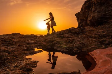 Crédence de cuisine en verre imprimé les îles Canaries Silhouette of mother and son walking in the sunset on the beach of Tacoron in El Hierro, Canary Islands, vacation concept, orange sunset, walking by the sea pointing the path