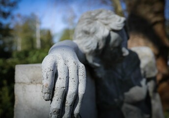 Of a hand of a statue leaning against a weathered stone wall
