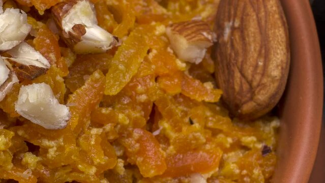 Gajar ka halwa is a carrot based sweet dessert from India. Garnished with Cashew and almond nuts and Served in a bowl over black background. Selective focus.