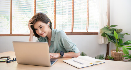 Portrait of woman work at laptop indoor at home cafe table wear wireless ear pods. Happy young asian girl student wear headphone watch webinar conference video call. Sme freelance work space concept