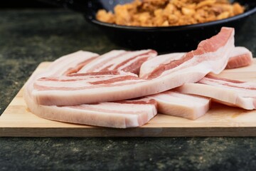 Cutting board with a freshly cut bacon slices, ready to be cooked
