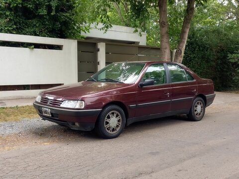 Old red 1995 Peugeot 405 SRI saloon, sedan in the street. Sunny day. Classic car.