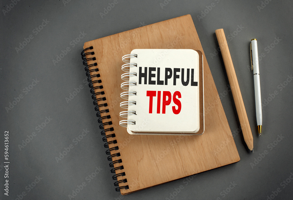 Poster helpful tips text on notebook with pen and pencil on grey background