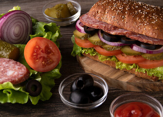 photo sausage and vegetable sandwich lying next to a plate of food