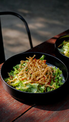 deep fried enoki mushroom or golden needle mushroom on top of green salad on black plate, vegan style
