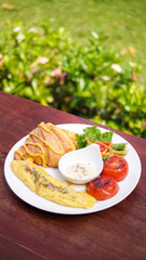 breakfast dish with savory croissant with Omelette, served with fresh healthy salad on a white plate and dipping sauce
