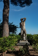 Statue of Creugante in the park surrounded by lush, green trees