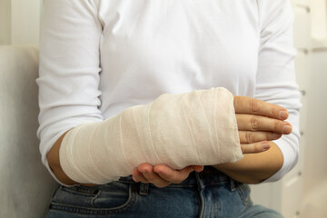 Close-up of a broken arm of a woman in a cast in a white t-shirt on a white background. Accident insurance. Insurance medicine concept.