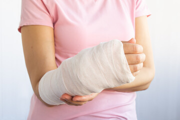 Close-up of a broken arm of a woman in a cast in a pink t-shirt on a white background. Accident insurance. Traumatology and insurance medicine.