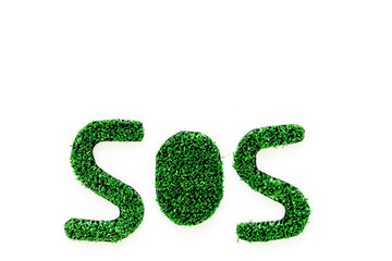 Word SOS made of green grass. Save the Earth planet ecology concept.