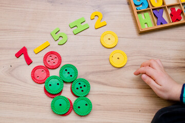 Math with fun. Counting and marking large buttons with colored numbers of natural wood. DIY game....