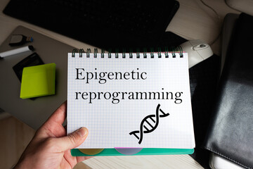 Epigenetic reprogramming word on notebook holding man against desktop.