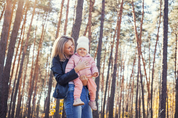 Fototapeta premium mother and little daughter are walking in a pine forest