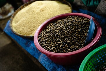 Coriander seeds displayed in a market in a red bowl