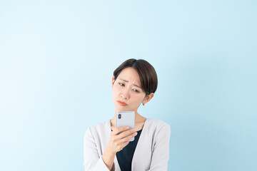 スマホを見て悩むビジネスウーマン