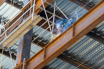 Construction worker using an angle grinder on a scaffold