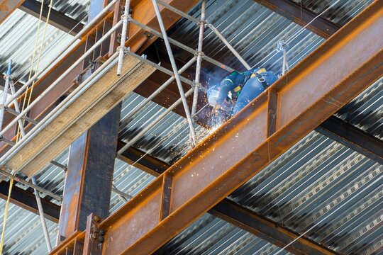 Construction worker using an angle grinder on a scaffold