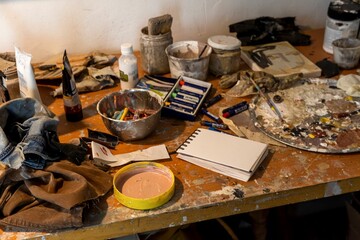 Wooden table filled with various art supplies cluttered across the surface