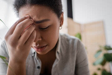 Young multiracial woman with mental problem sitting at home.