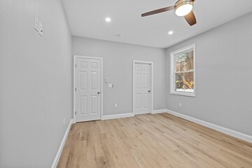 Empty room with wood floors and a ceiling fan in front of a window