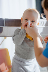 Adorable baby boy blowing nose into tissue paper by his mother at home.