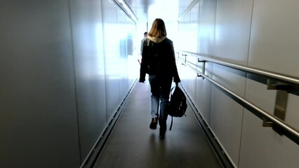 Woman walks through corridor to board plane in airport terminal. Flight to vacation destination. High quality 