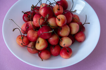 Fresh ripe cherries in a white plate on a purple background. Vegetarian breakfast. Healthy food. Close-up.