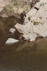 Pescatore all'azione mentre pesca a spinning sul bordo roccioso di un torrente di montagna