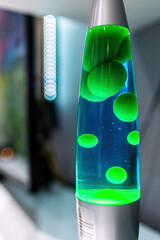 Lámpara de lava verde y azul brillando en una habitación moderna, creando un ambiente relajante y...