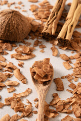 Coconut chips with cinnamon in wooden spoon, home drying. Vegan and sugar free dessert. Vertical format. Sri lankan local snack. Tasty snack add to garnish your dessert.