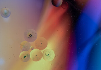 Abstract spots and circles of paint similar to planets on the surface of water.