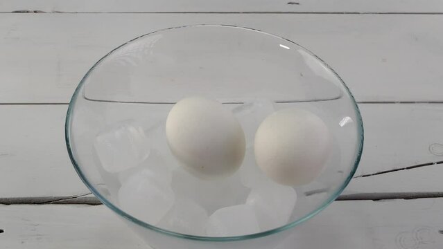 Boiled eggs are put in bowl with ice and poured.