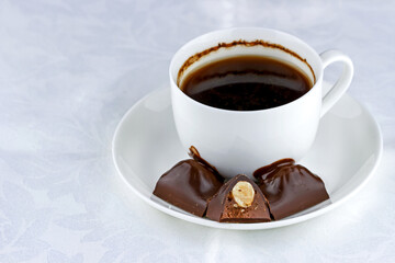 Started cup of coffee with chocolates on a saucer.