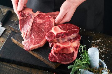 Steak beef meat. Chef cutting steak beef. Mans hands hold raw steak Tomahawk on rustic wooden...