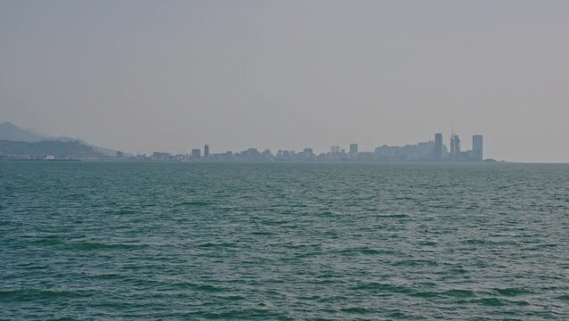 Silhouette of a metropolis by the sea in a atmospheric haze or smog