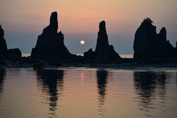 早朝の海岸に立つ奇岩