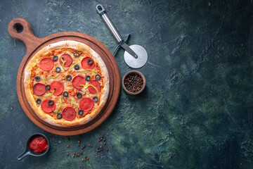 Delicious pizza on wooden cutting board and pepper ketchup on the right side on isolated dark background
