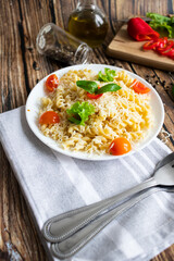 Macaroni with cheese and vegetables. On a wooden background