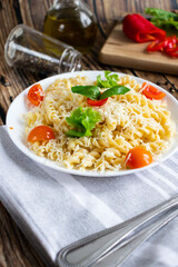 Macaroni with cheese and vegetables. On a wooden background